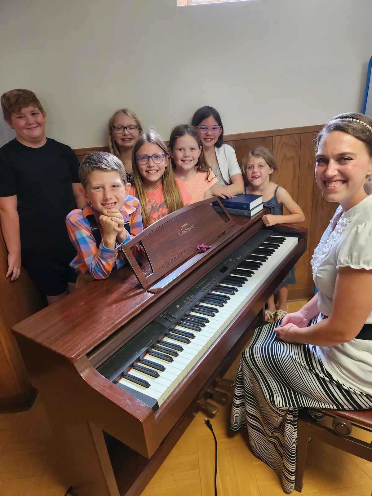 Children and their teacher gathered around a piano at Sunday School.