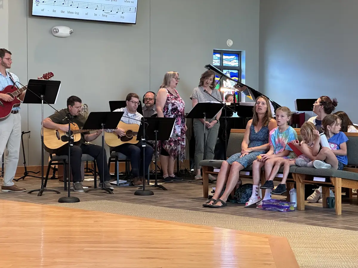 The praise band and singers leading worship, with families singing along.
