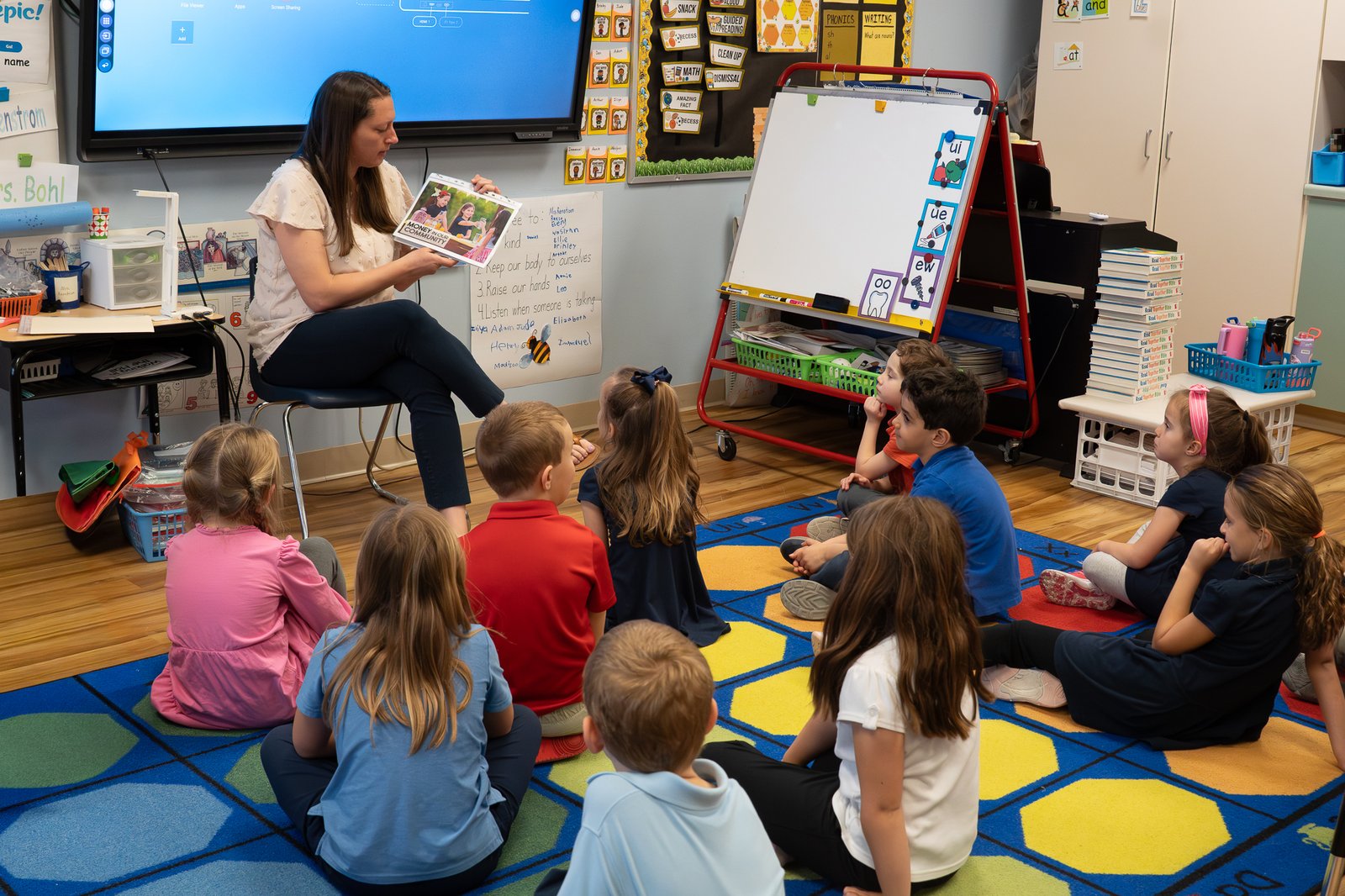 A teacher reading aloud to a circle of young students