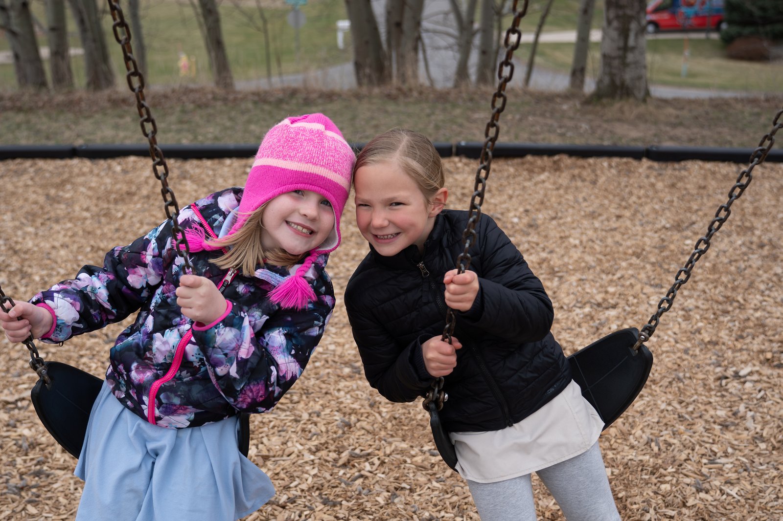 Two students laughing together on the playground swings